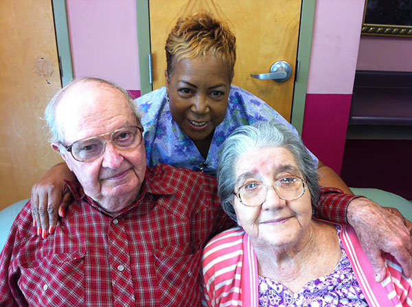 caregiver and two residents smiling at the camera
